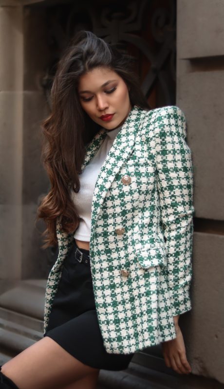woman posed against a wall wearing a mini skirt and houndstooth blazer