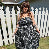 Person wearing a floral dress standing in front of a white picket fence